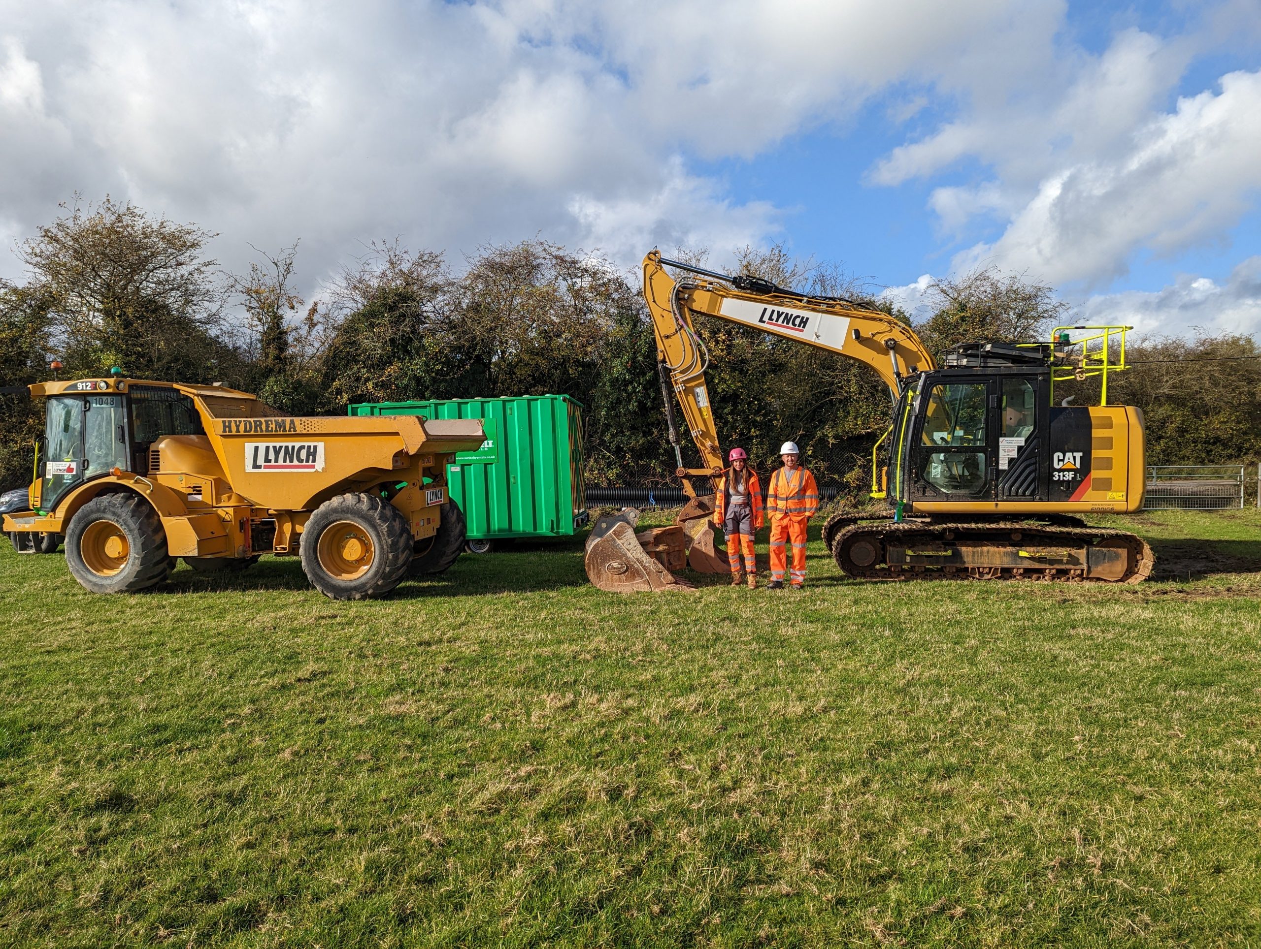 Two people in hi-vis standing in front of machinery before works start