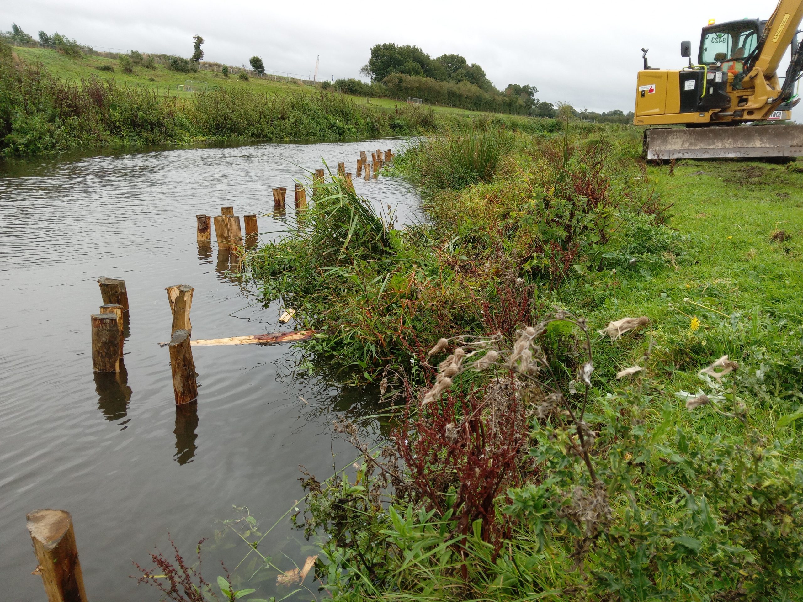 Posts installed in the river and a digger on the river bank